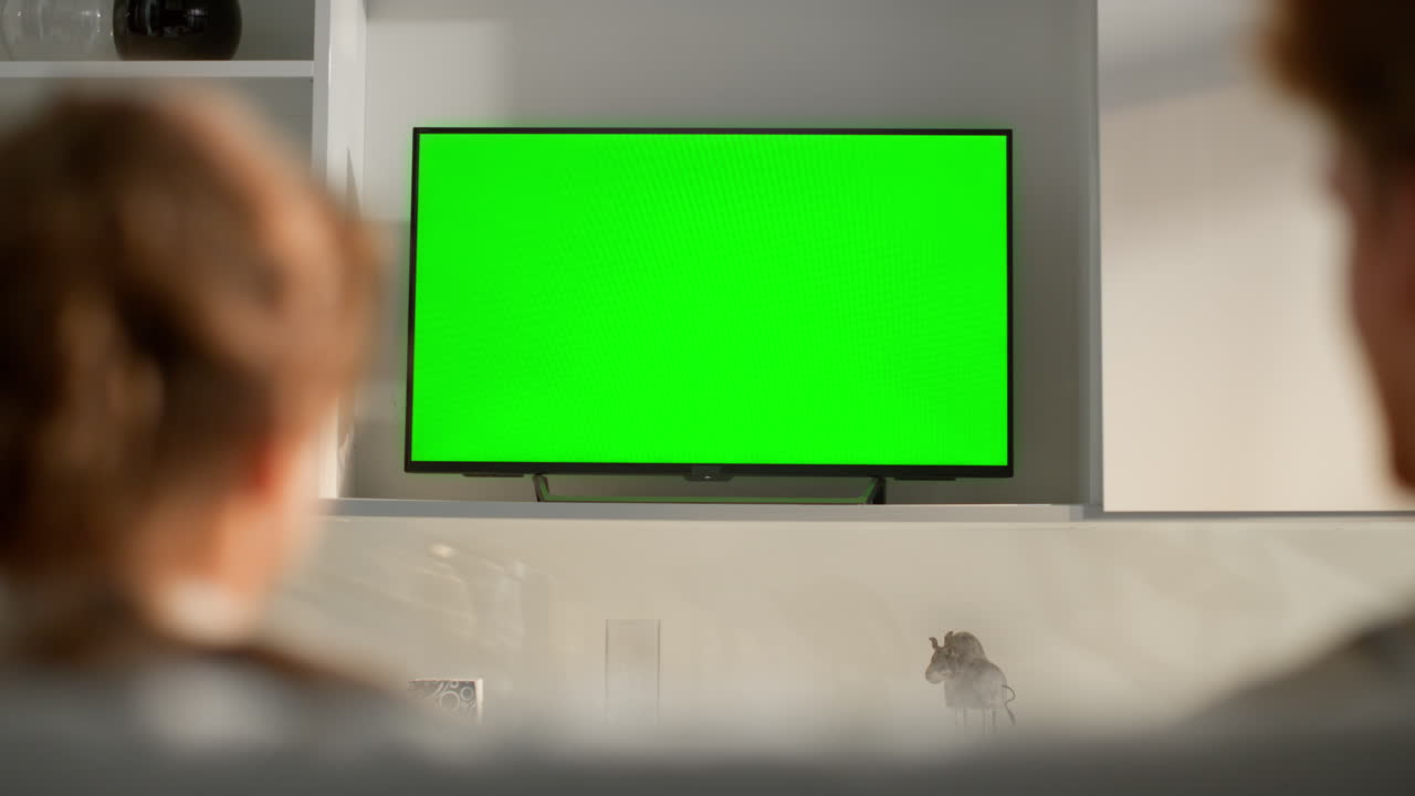 Couple relaxing watching green screen tv in living room. Caring man embrace girl