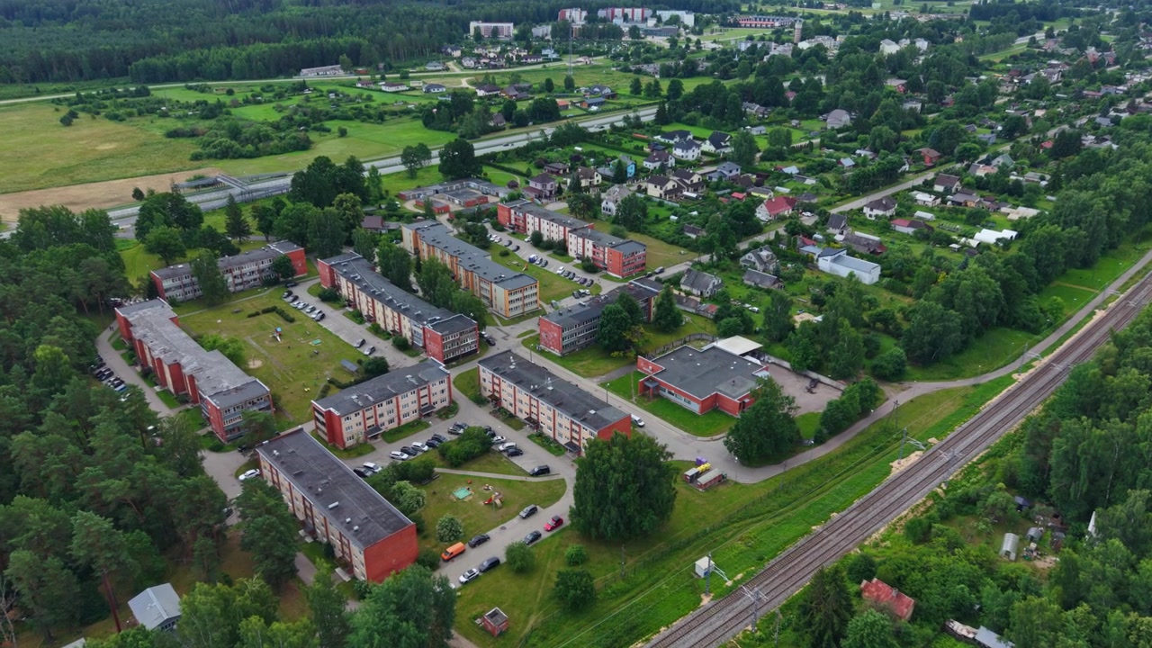 Drone establishing shot, Jaunolaine with homes, railway and surrounding forests