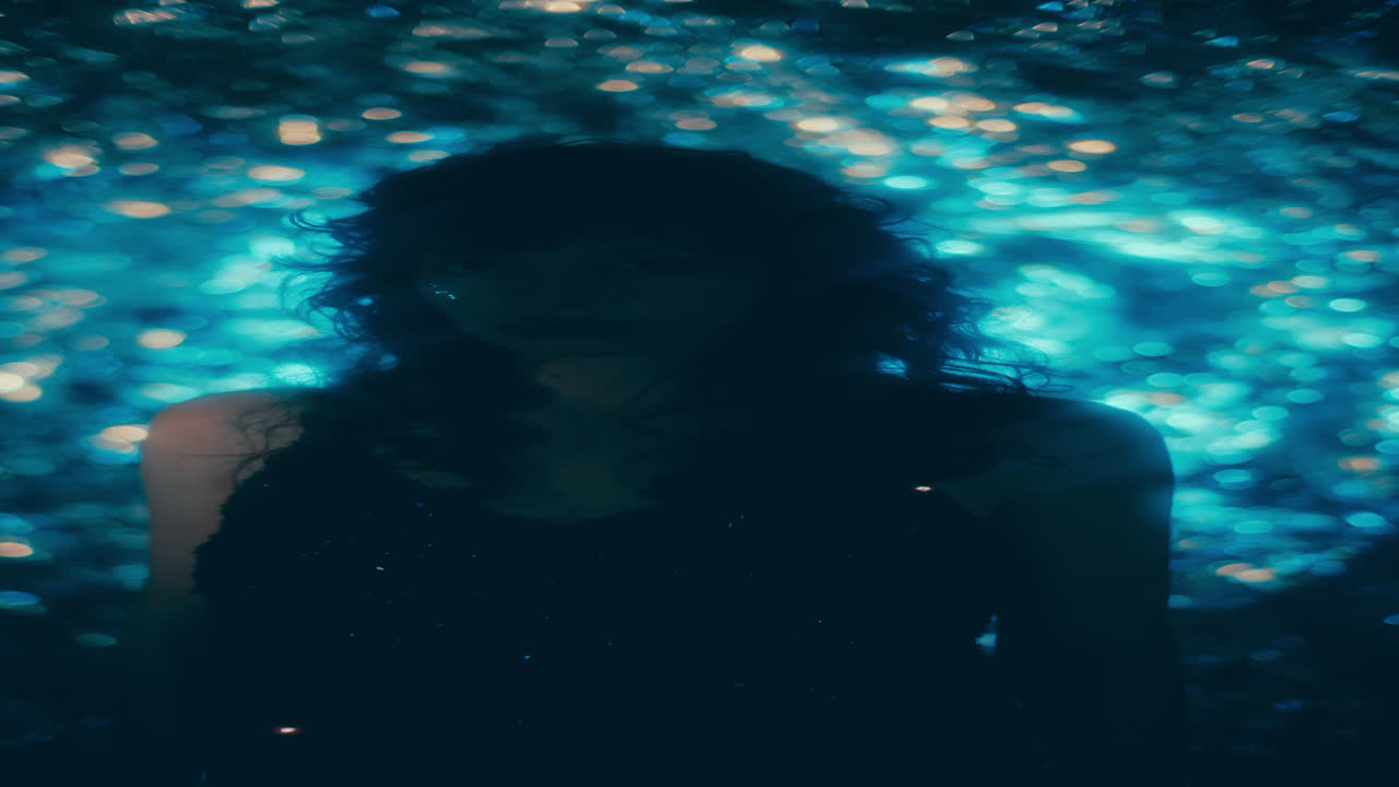 Portrait of Young Woman in Shiny Dress against Sparkly Bokeh Lights