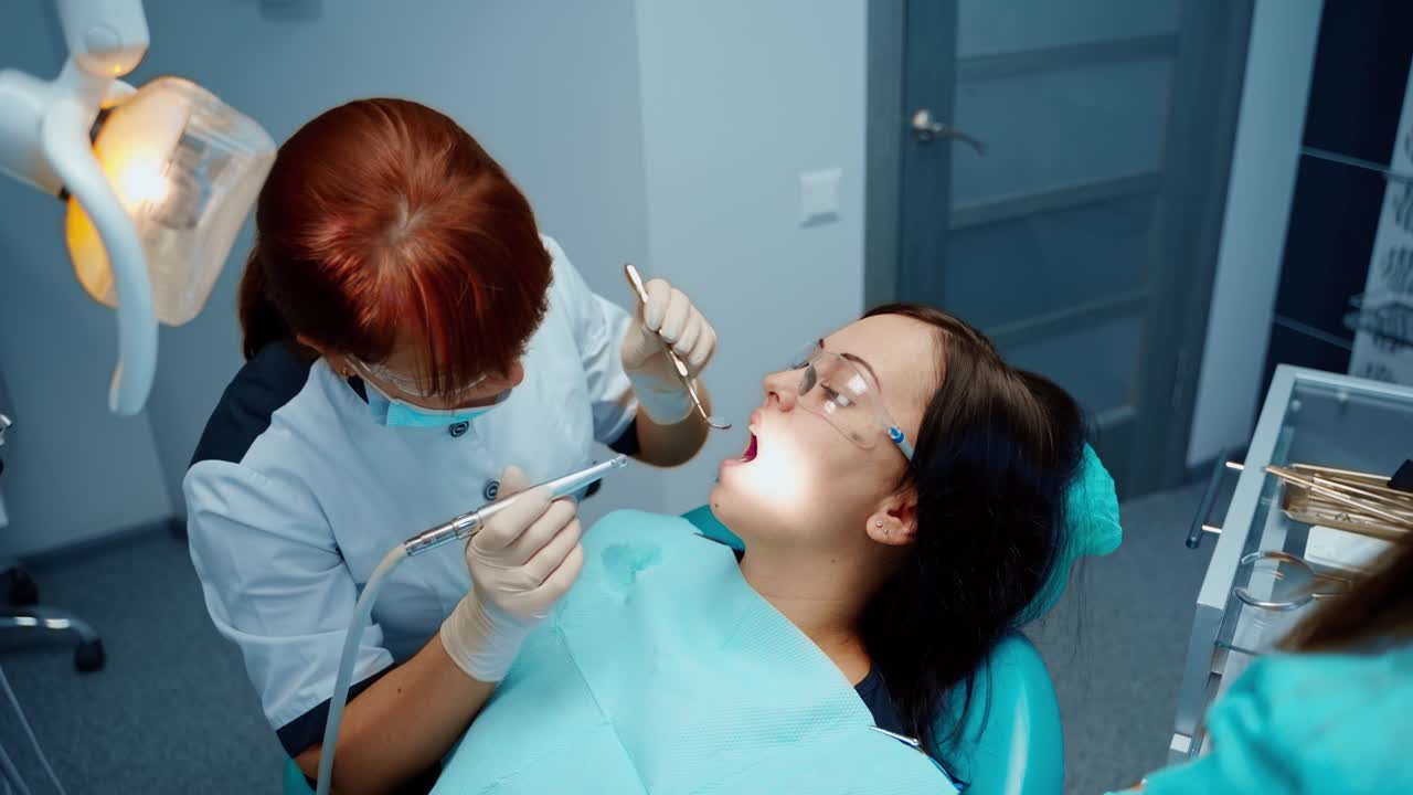 Young woman visits stomatology cabinet. Dentist in sterile gloves treating girl's teeth at a dental clinic. Dentistry concept.