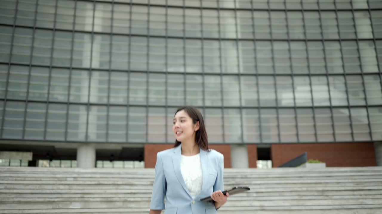 hermosa mujer de negocios con tableta caminando en el pasillo entre los edificios en el centro de la ciudad. mujeres confiadas caminan hacia sus objetivos para el éxito en la ciudad.