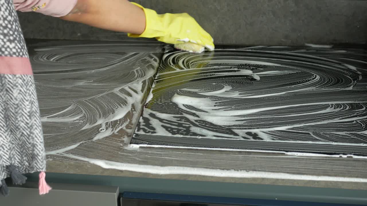 limpiando una estufa de la cocina con jabón y esponja