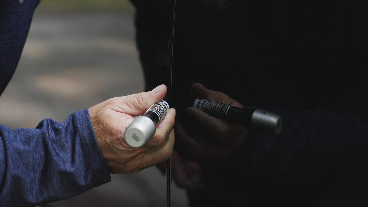 Slow motion action as a man repairs a spot of chipped paint oh his vehicle.