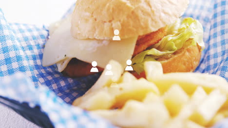 hamburguesa y papas fritas con personas iconos de animación sobre mantel a cuadros