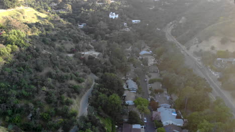 aerial of neighborhood houses and street nestled in a valley between mountains