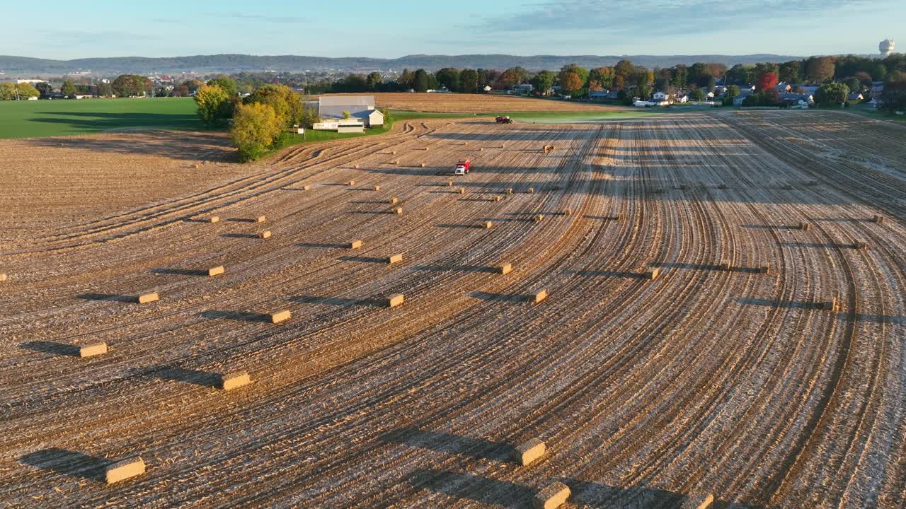 끔 한 구 이 있고, 어져 있는 풀 어리 들 과 해 가 지는 트랙터 가 있는 농장 의 공중 사진