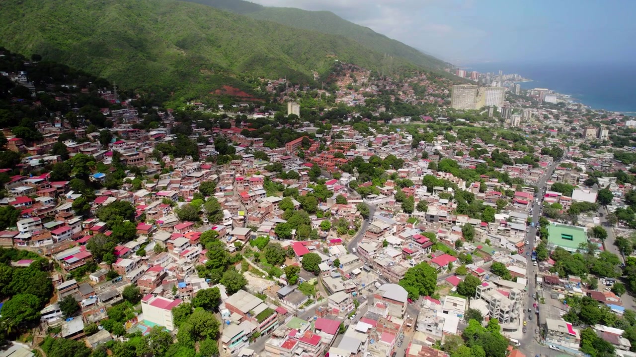 Drone-seuranta La Guairan yllä Venezuelassa, korostaen kontrastia ehjien rinteiden asuinalueiden ja maanjäristyksen vaurioittamien rannikkoalueiden välillä