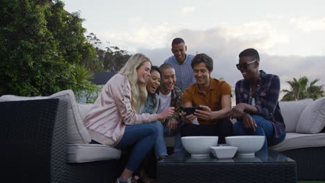 group of friends using a smartphone and discussing on a rooftop