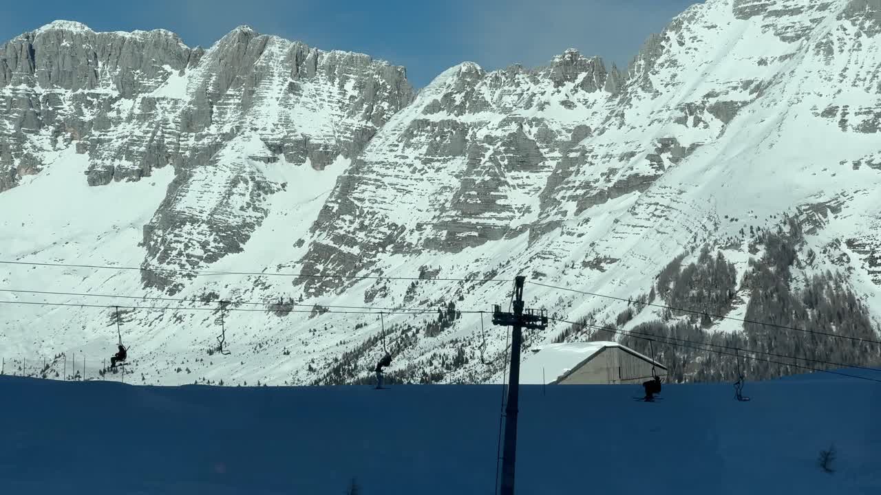 Skier on a chairlift in silhoutte. Italian Alps