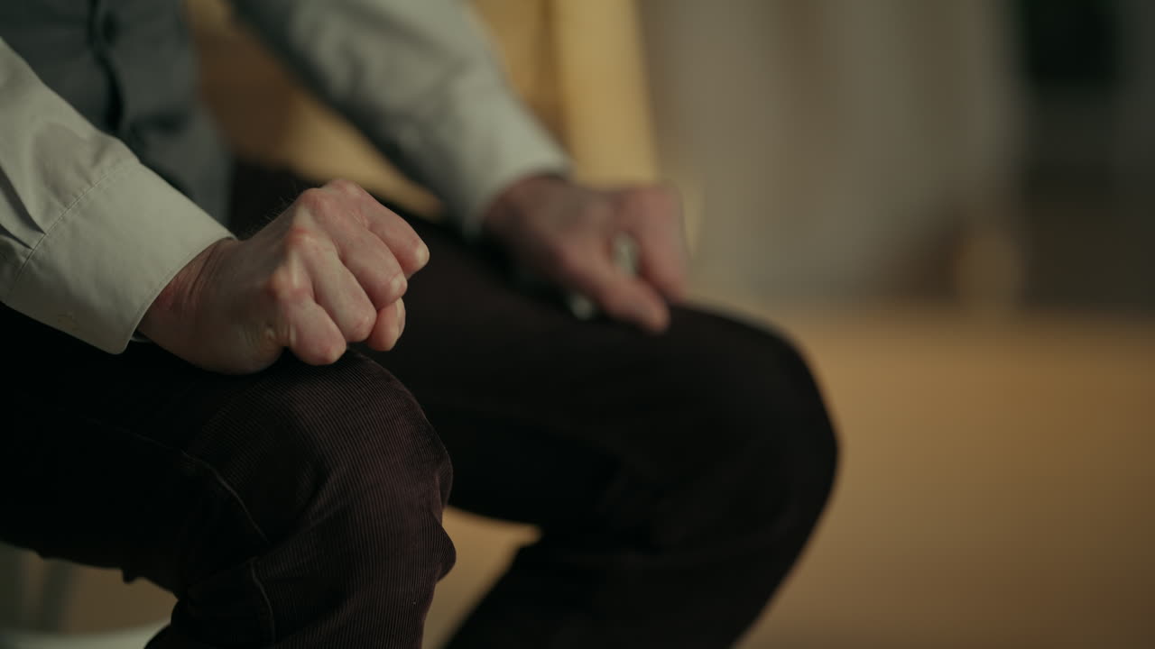 Ængstelig hånd knytter sig og slapper af på et knæ