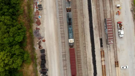 4k top down view showing train cars leaving a train station withmultiple tracks alongside