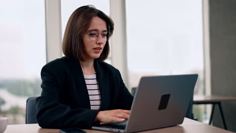 modern good-looking young woman working in the office. smiling lady typing on laptop.