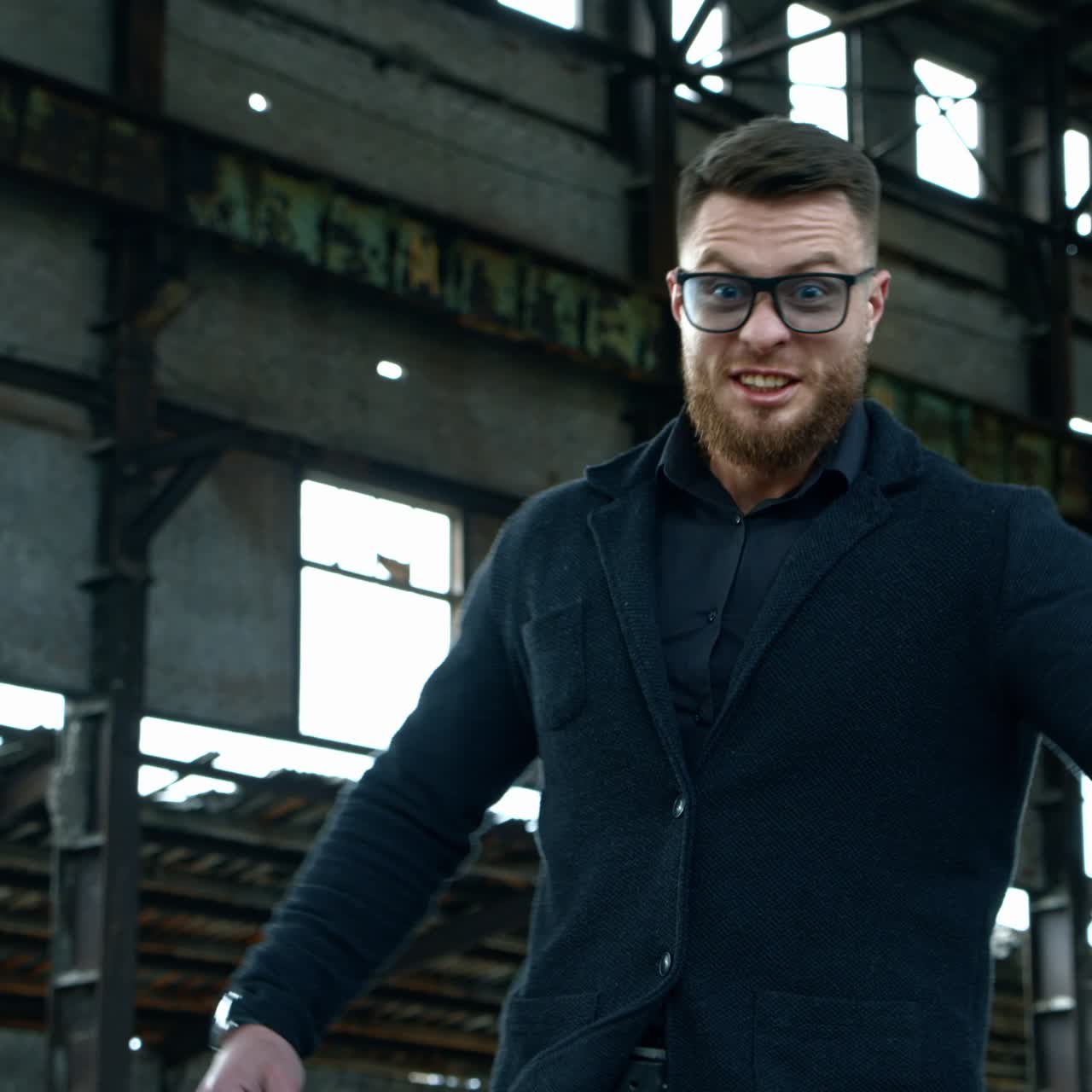 Strong bearded young man with bat. Guy waves a baseball bat on the background of abandoned house. Bandit looks at camera and shouts.