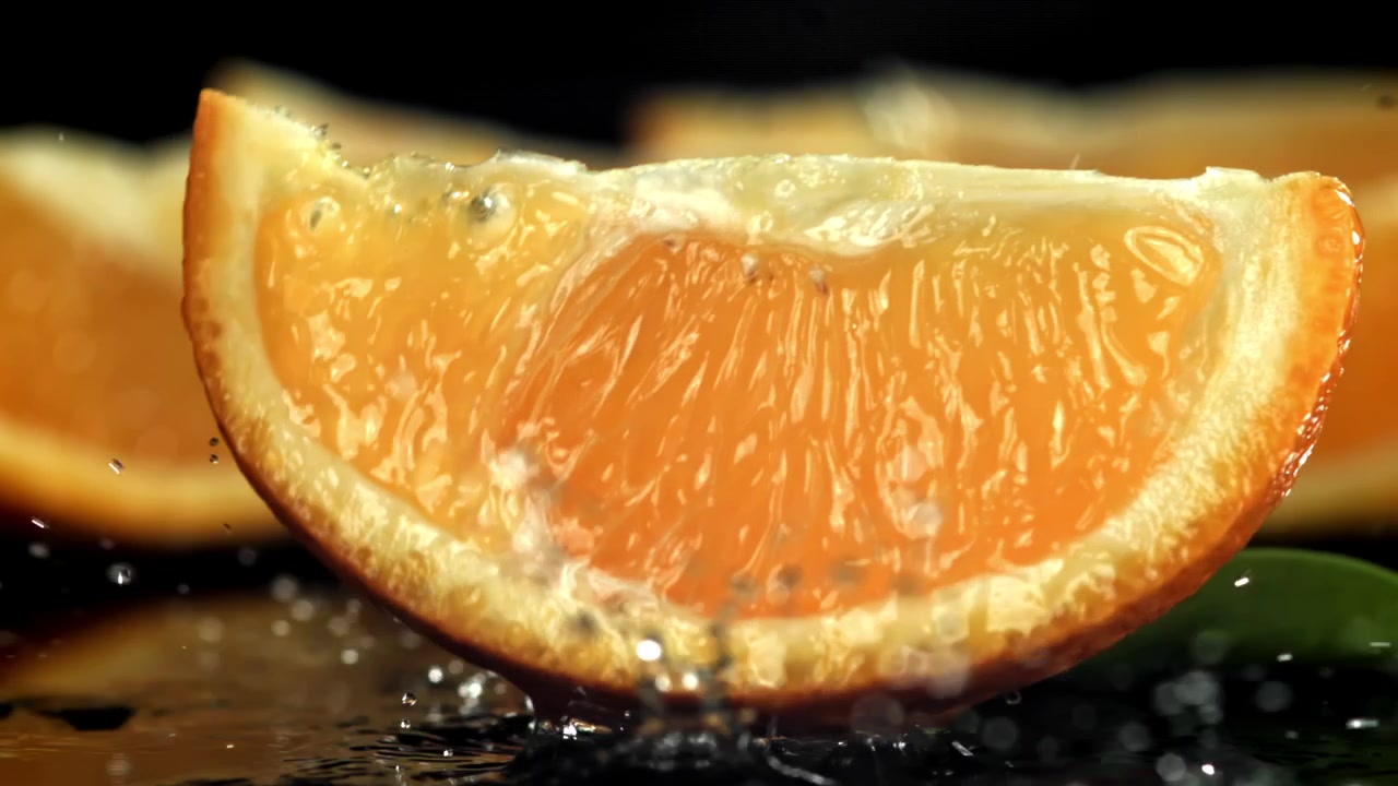 Fetta d'arancia fresca che si tuffa nell'acqua su sfondo scuro