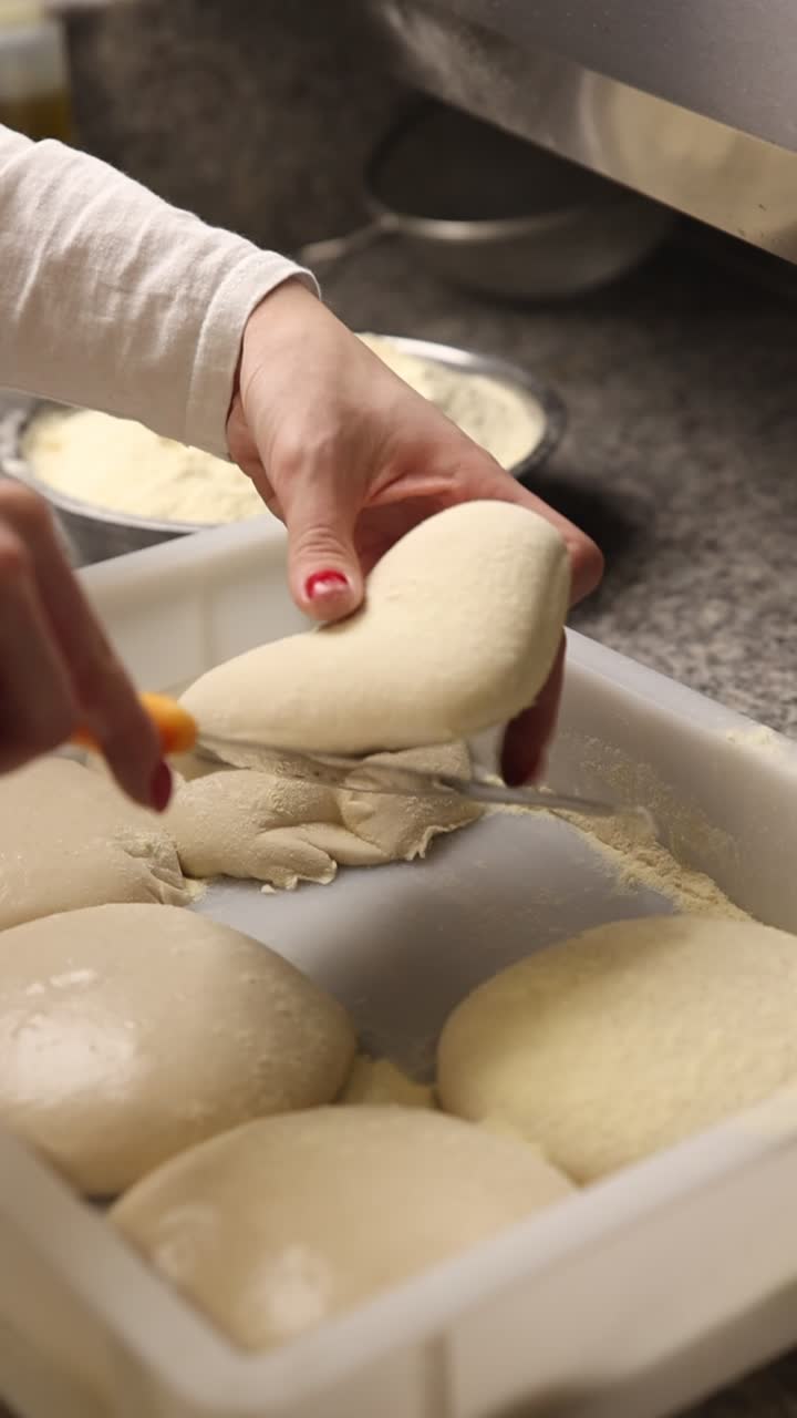 Close-Up of Hands Preparing Pizza Dough Balls in a Kitchen