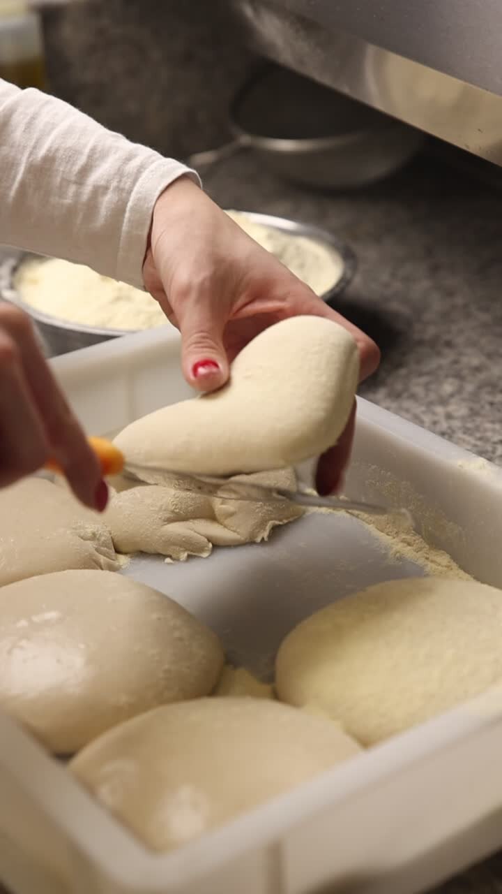 Close-Up of Hands Preparing Pizza Dough Balls in a Kitchen
