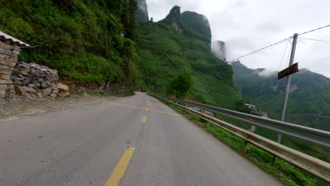 scooter riding on winding road through mountains and valley in ha giang loop in vietnam. pov shot