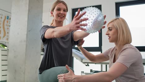 female physical therapist working with young woman using exercising ball.