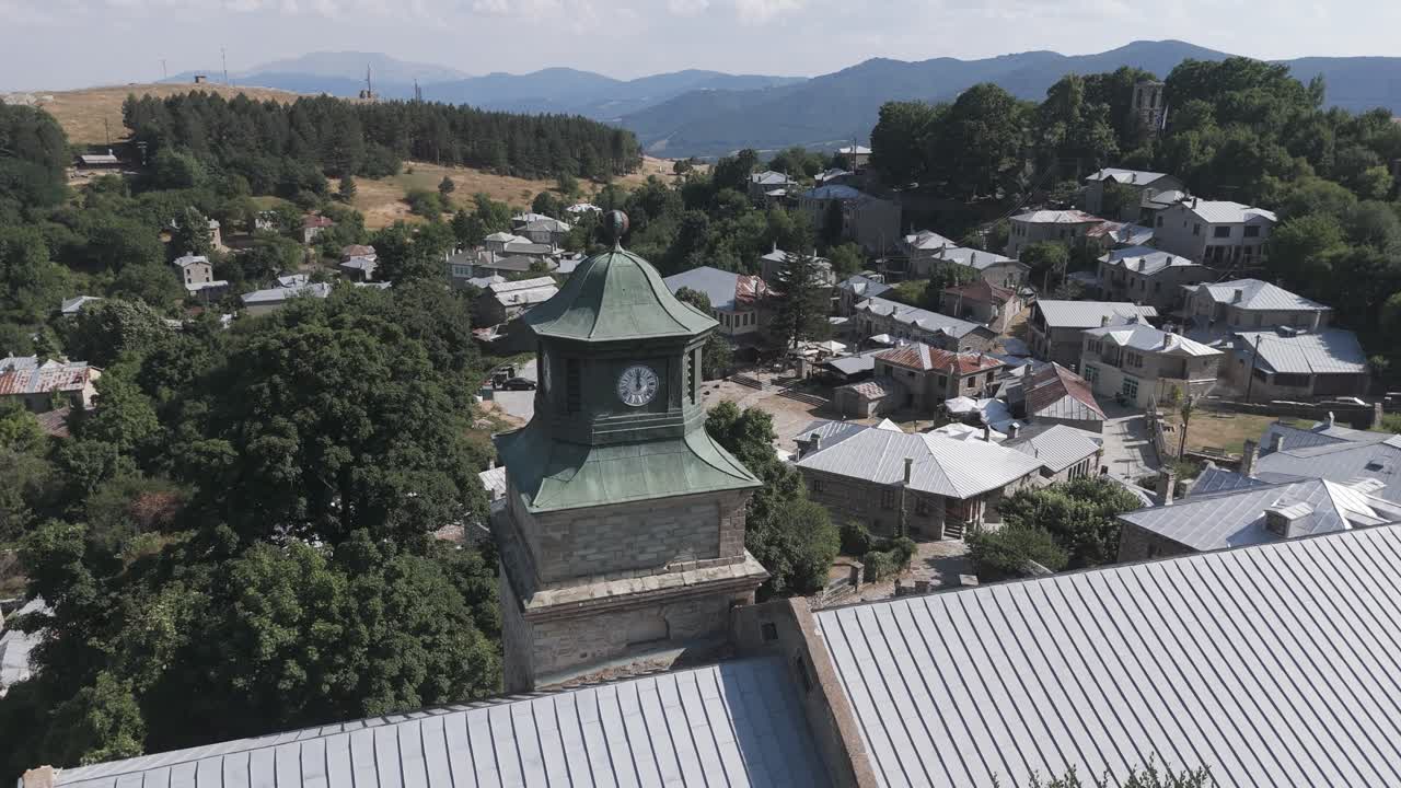 Clock tower with green roof, surrounded by trees and houses, drone shot