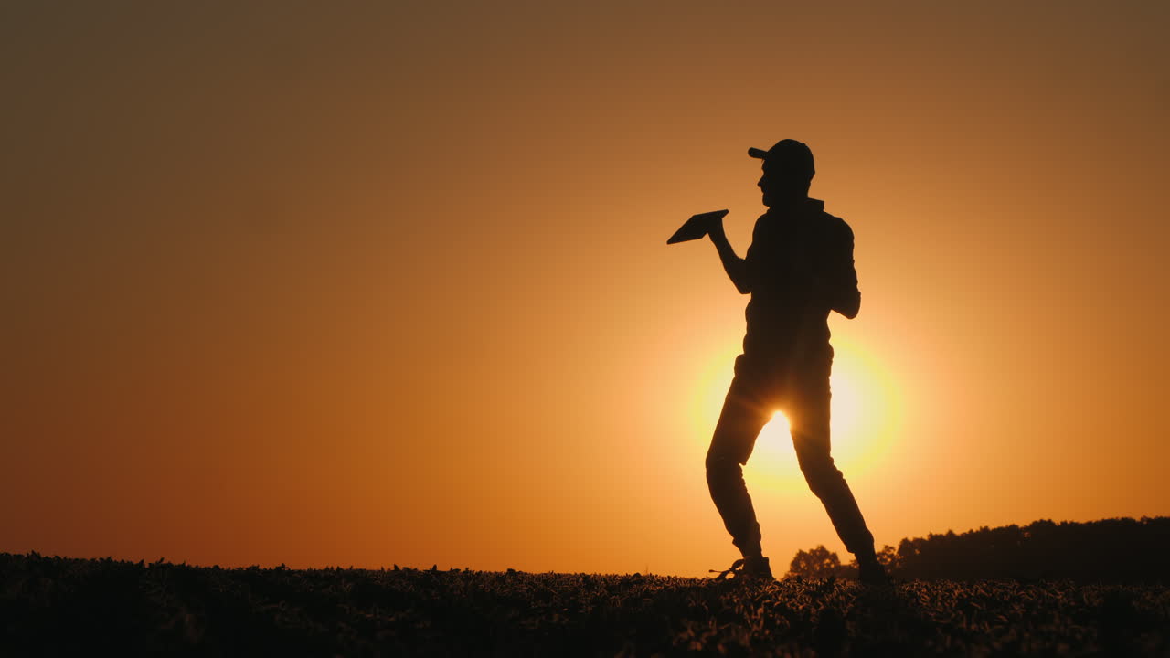 태블릿으로 해가 지는 것을 축하하는 농부