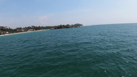 Aerial-dolly-in-of-skilled-man-riding-a-jet-sky-in-deep-turquoise-sea-near-the-coast-of-Mirissa-beach-at-daytime,-Sri-Lanka