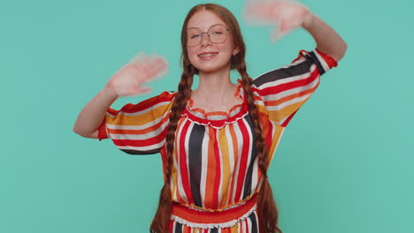 Redheaded-girl-smiling-friendly-at-camera-and-waving-hands-gesturing-hello-or-goodbye,-welcoming