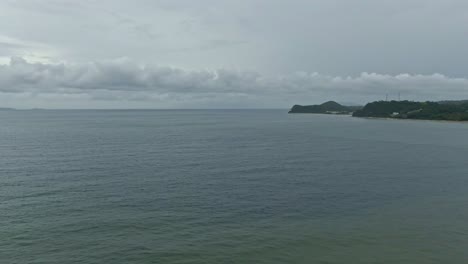 Scenery-shot-from-beautiful-white-beaches-to-silhouette-Island-under-cloudscape-surrounded-by-the-ocean