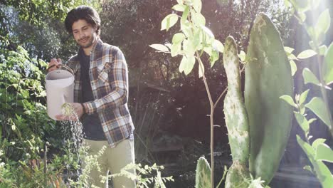 hombre caucásico feliz regando plantas en un jardín soleado, cámara lenta