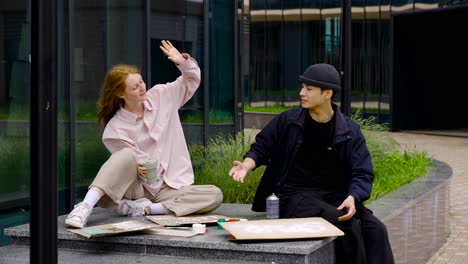 ginger woman drinking coffee and man painting board doing high five