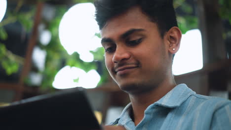 under shot of light skinned young lad in casual setting smiling while watching tablet screen glowing softly capturing sense of joy engagement and modern learning in intimate low angle tech portrait