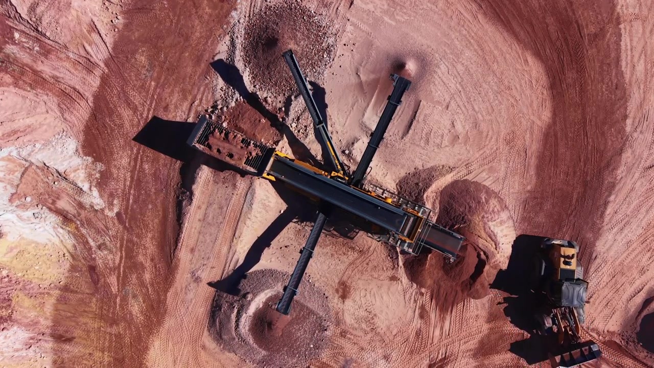 Top-down view of a multi-deck mobile screening plant with radial discharge conveyors separating clay and soil at an open-pit mining quarry