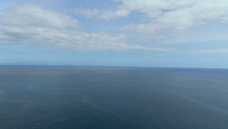 wide aerial shot of ocean and horizon with soft cloud formations in a bright blue sky, ideal for visual overlays, b-roll backgrounds or motion graphics templates.