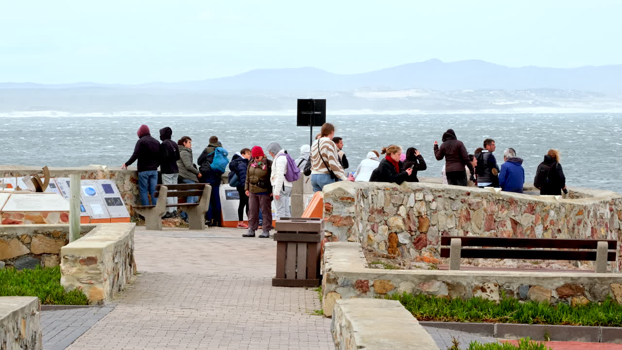 Travelers at Hermanus Gearings Point lookout do whale watching. Telephoto view