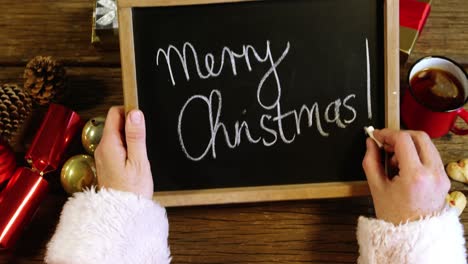 Santa-claus-writing-merry-christmas-on-slate