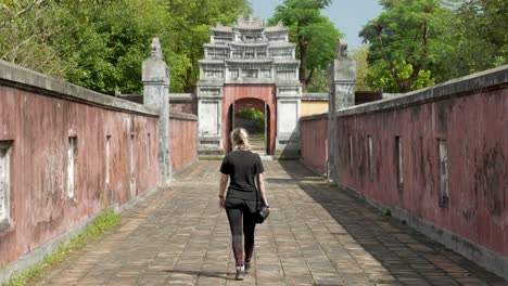 Young-woman-walking-towards-temple-entrance-in-the-city-of-Hue,-Vietnam