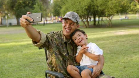 feliz padre militar discapacitado en silla de ruedas tomando selfie con su hijo