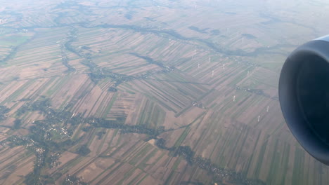 aerial view of wind farm through fog from glass window of airplane in flight