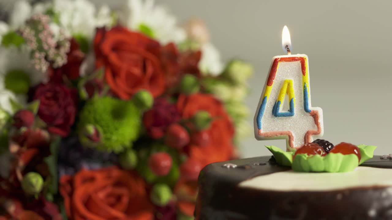 dolly: arreglo de flores y pastel de cumpleaños con vela encendida número 4