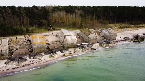 aerial view of abandoned seaside fortification building at karosta northern forts on the beach of baltic sea in liepaja in overcast spring day, wide drone shot moving forward, tilt down