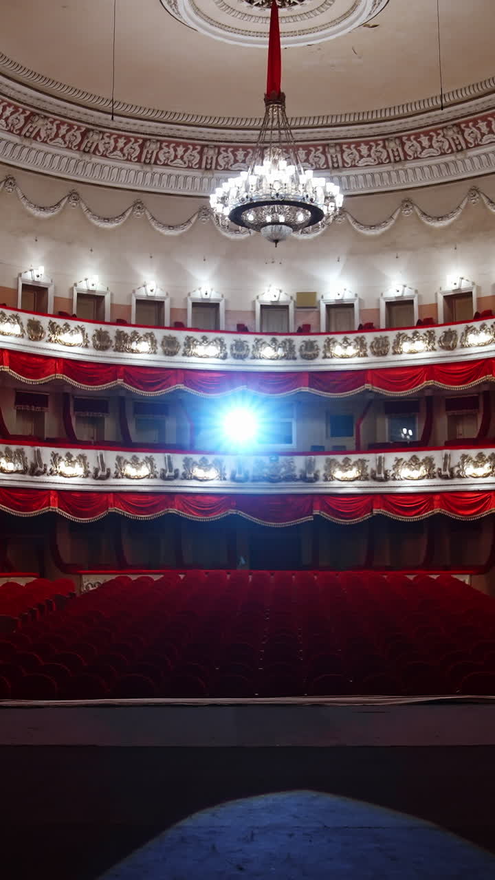 Selective focus from stage on empty rows with red velvet seats in theater hall. Rows with empty chairs. No people because of covid-19. Vertical video