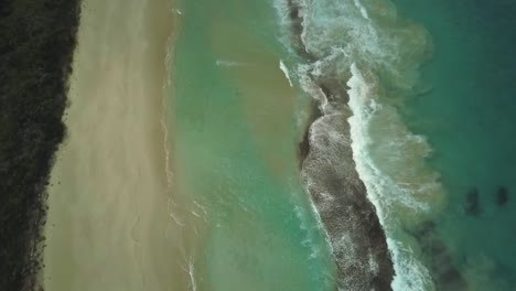 Vista-Aérea-De-Las-Olas-Del-Océano-Rompiendo-En-Una-Gran-Playa-Vacía-En-El-Oeste-De-Australia.