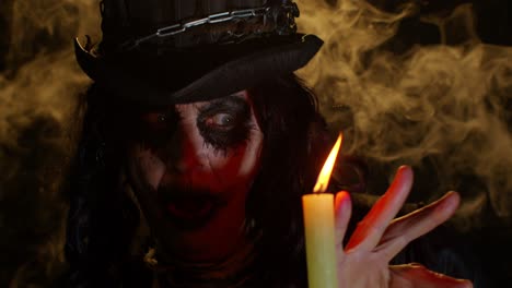 Frightening-creepy-senior-woman-with-Halloween-witch-makeup-looking-at-candle,-conjure,-hex,-wiz