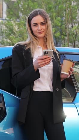 woman standing by electric car, focused on phone while charging. vertical video