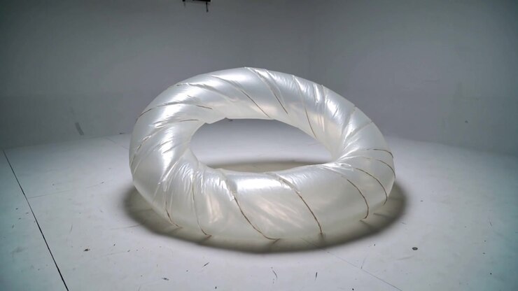 Animating translucent torus rotating and expanding on white studio floor, revealing spiral seams