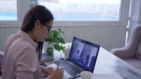 e-learning, joven con gafas pasa la enseñanza en línea para el auto-desarrollo utiliza computadora portátil y hace notas en un cuaderno