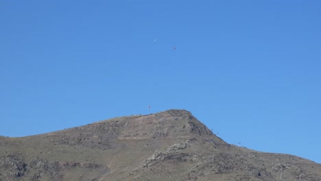 paragliders ride thermals and cast shadows on volcanic peninsula on a sunny day - christchurch (new zealand)