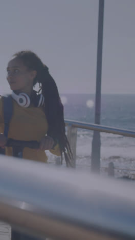 animation of light spots over smiling biracial woman walking with scooter on promenade