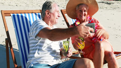 senior couple taking selfie on mobile phone while having cocktail