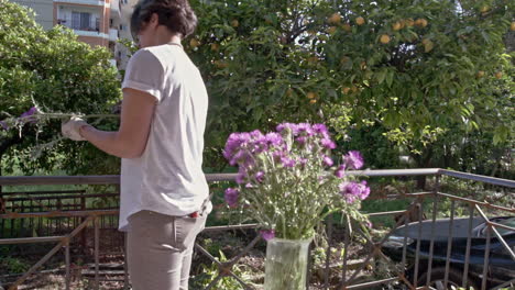 woman decorates a vaze with wildflowers at a porch of a countryhouse 60fps