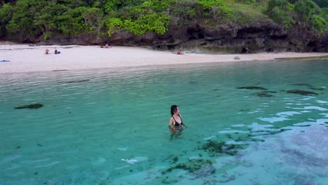 a woman on the turquoise ocean of gunung payung beach in bali, indonesia